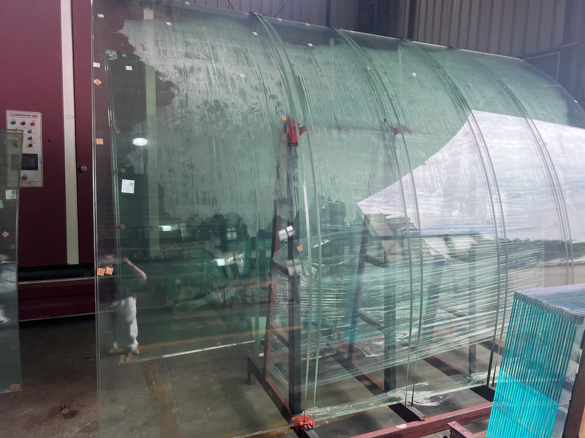 Curved glass panels on racks at the factory for the Tobago project